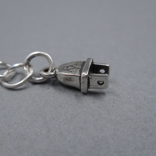Close up of plug charm from Forged Mettle Jewelry